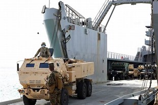 A Marine operating an armored vehicle aboard a ship.