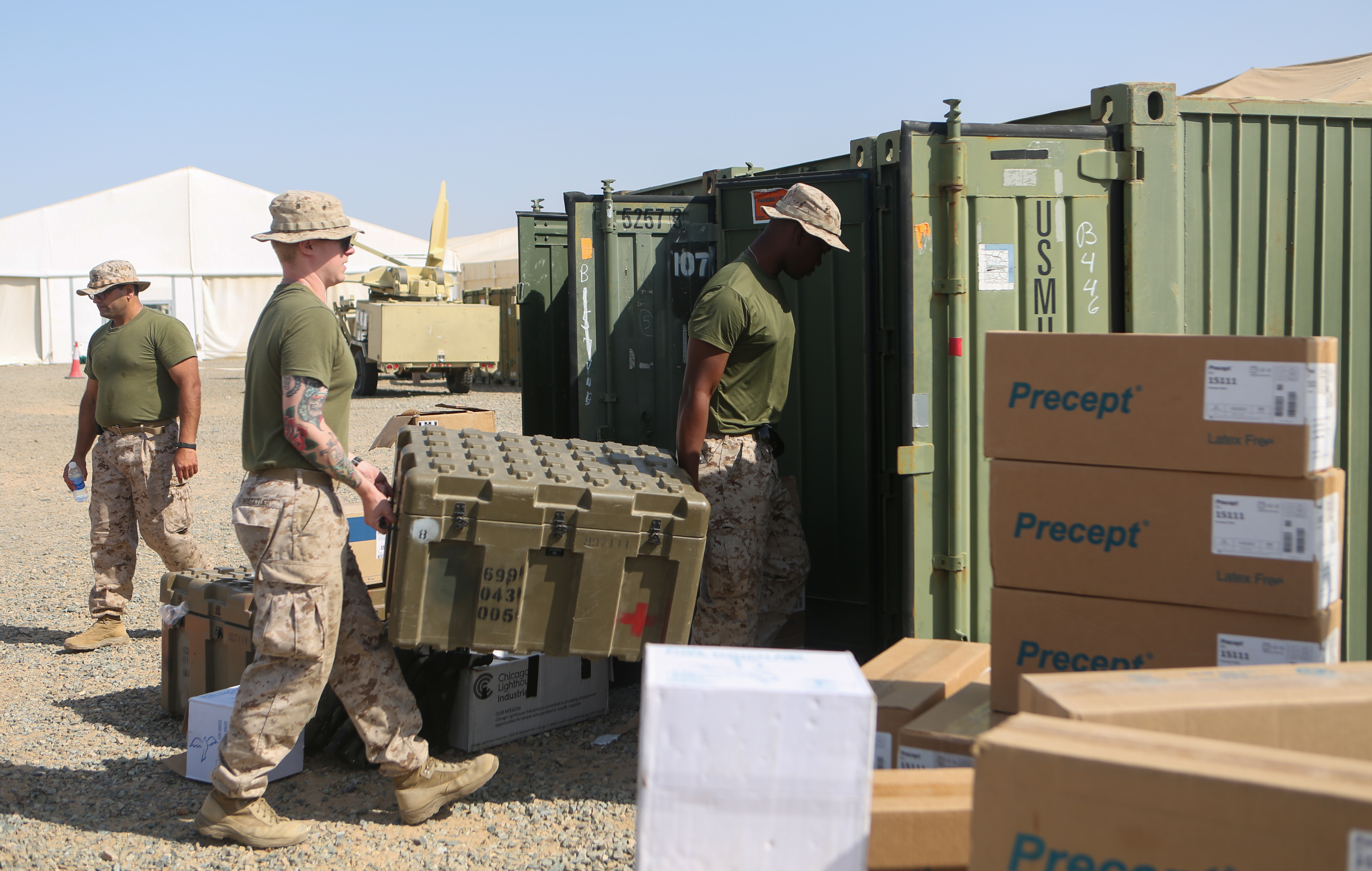 Two Marines carrying a large tote into a cargo unit.